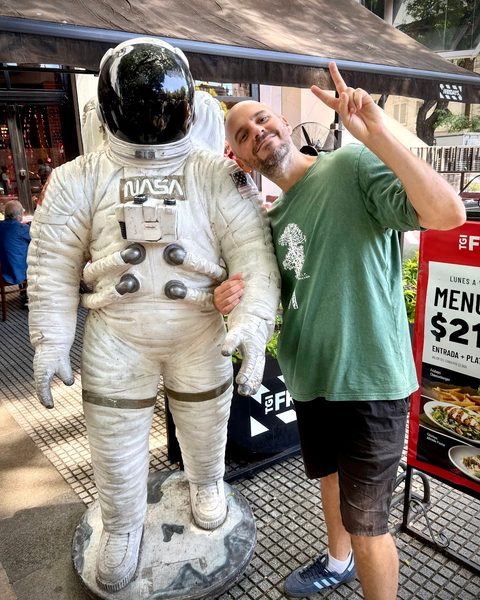 Juan making a peace sign next to an astronaut statue in a NASA suit