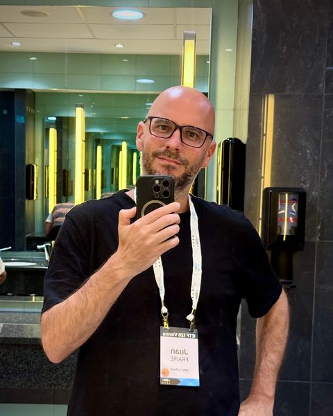 Juan taking a mirror selfie, wearing his IETF 126 Vienna badge